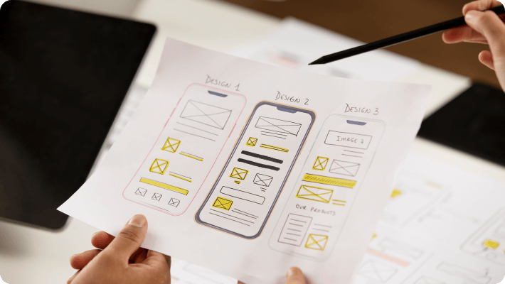 An individual holds a paper illustrating a website design, emphasizing the concept of digital creativity and development.