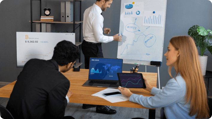 Several people gather at a table, focused on their laptops, fostering teamwork and collaboration in a modern workspace.