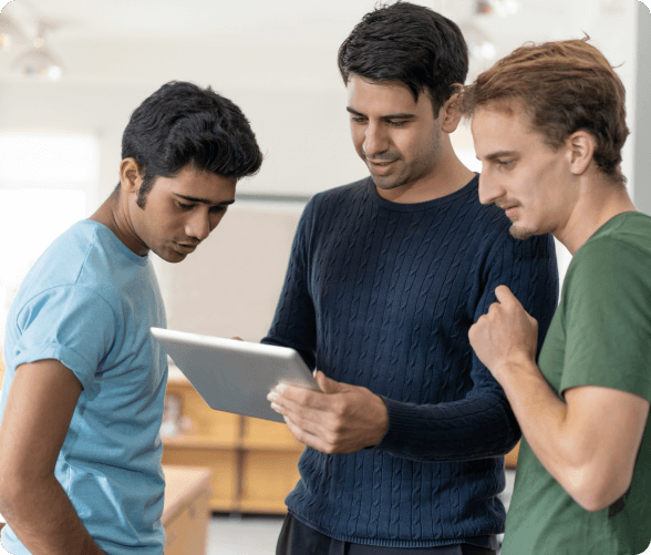 A group of three men focused on a tablet, sharing insights and analyzing the displayed information.