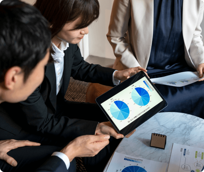 Three business professionals collaboratively examining a tablet computer in a modern office setting.
