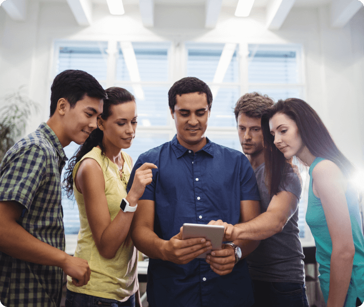 Young people collaborating and interacting with a tablet, showcasing teamwork and technology in a social setting.