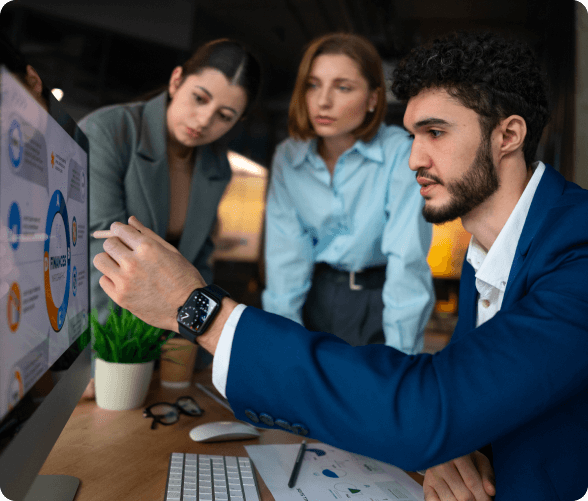 A trio of business individuals focused on a computer screen, engaged in discussion and analysis in a professional environment.