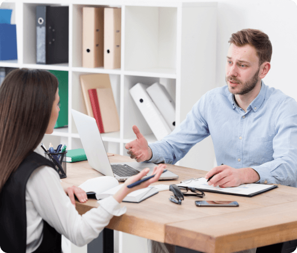 A man and woman at a table, collaborating on a laptop, showcasing teamwork and engagement in a professional setting.