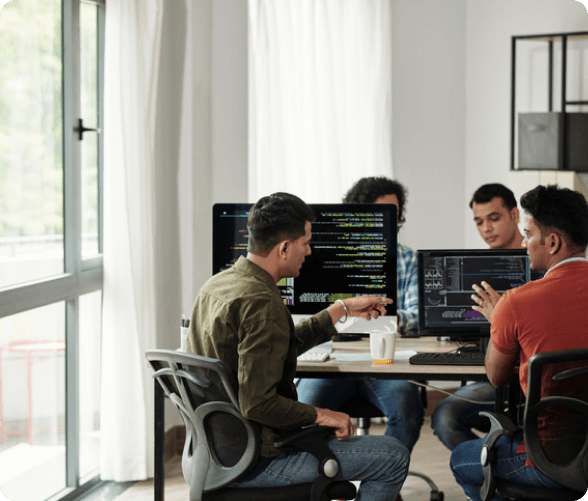 A group of four people at a table, focused on their computers, illustrating teamwork and productivity.