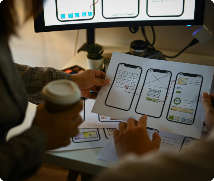 Two people engaged in work at a computer, with papers and a cup nearby, demonstrating teamwork and concentration.