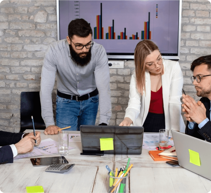 Business team engaged in a discussion while working together on a laptop in a professional environment.